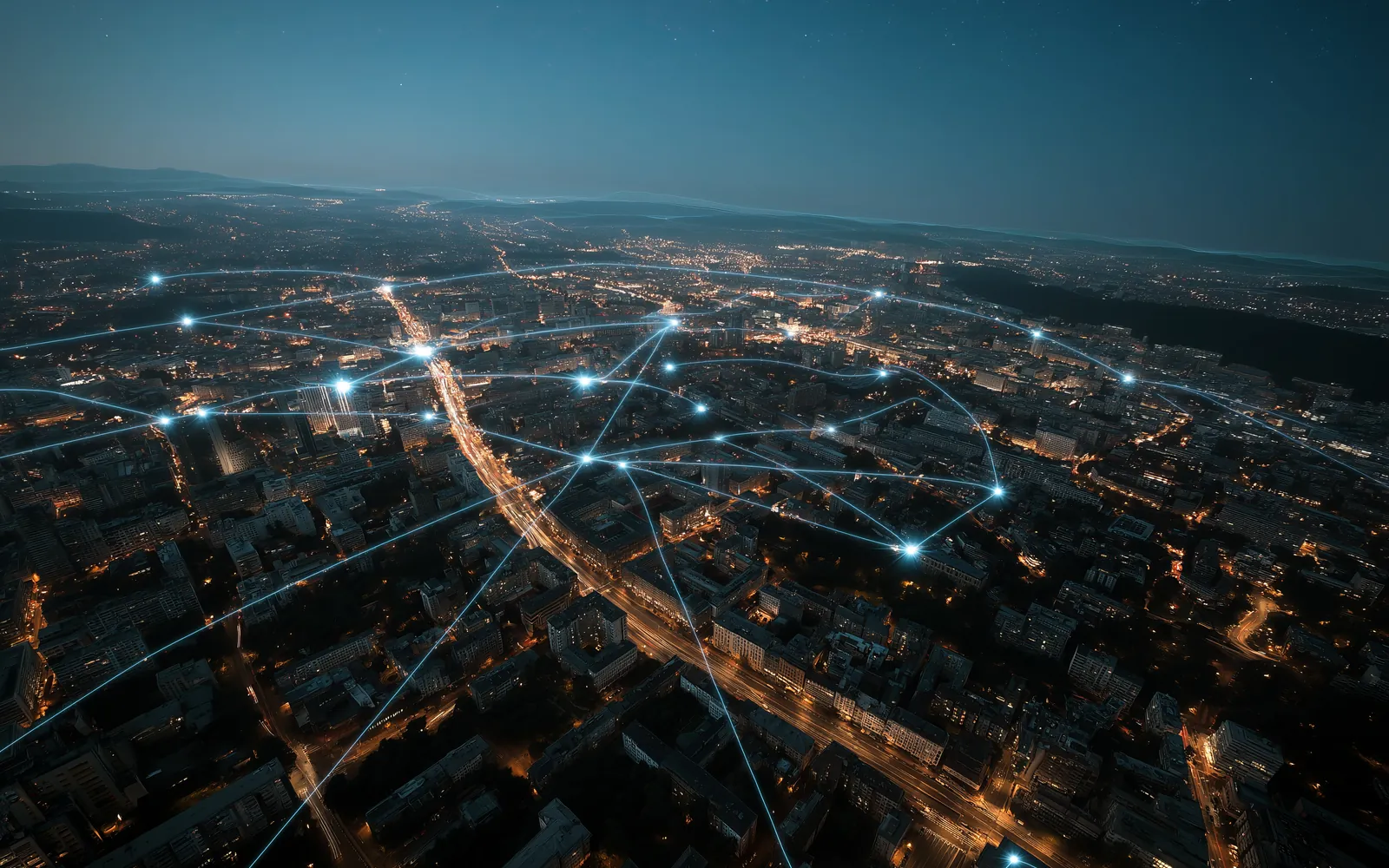 Night aerial view of a city with glowing lines linking its districts